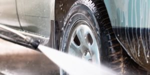 Car hand wash using high pressure washer High pressure water stream washing a car at handwash car station. Vertical close up crop
